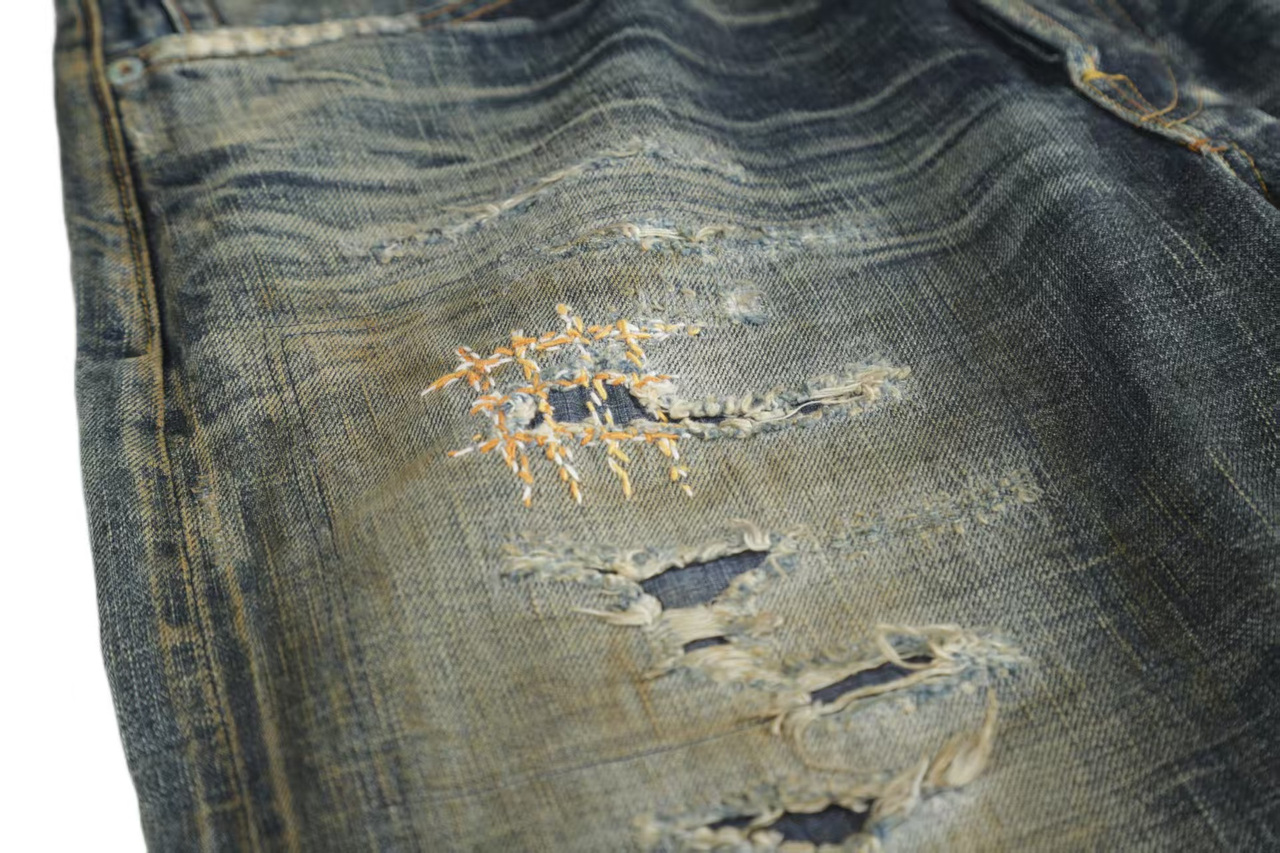 Indigo wash with pale abrasion, distressed areas and repair stitches
